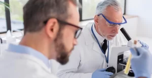 close up scientist working with microscope