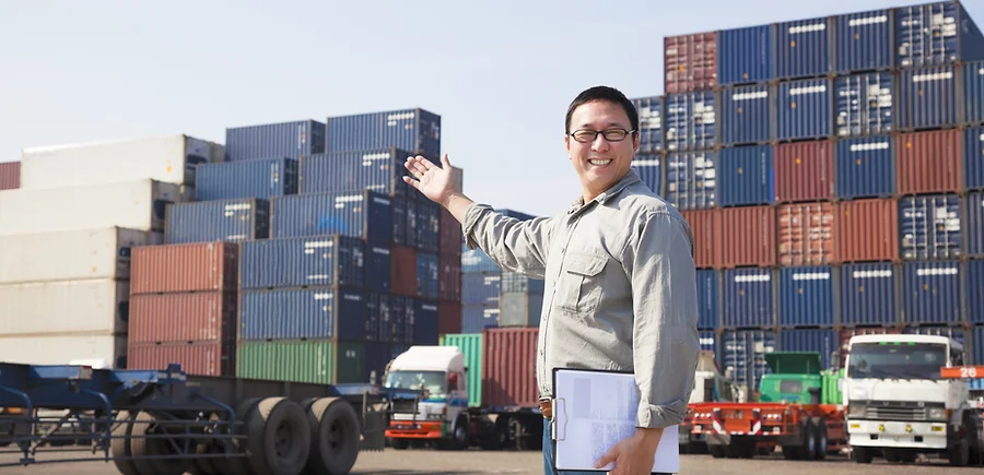 Smiling Asian Person Standing In Front Of Container Yard